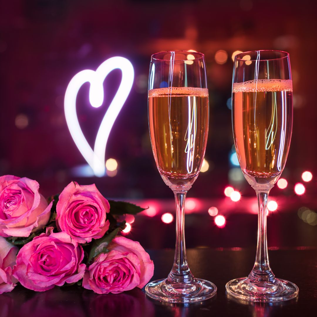 Romantisk belysning med en rosa led-lampa, rosa rosor och två glas rosé.